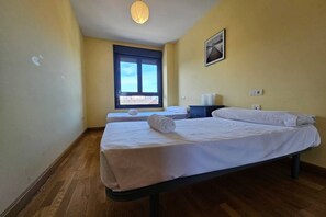 A bedroom with a bed, a window, a bedside table, and a wall-mounted picture.