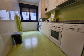 A kitchen with a washing machine, oven, and microwave.