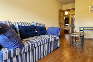 A striped sofa with pillows, a wooden floor, and a chair.