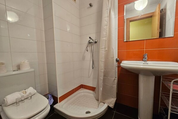 A bathroom with a shower, toilet, sink, and a mirror.