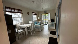 A room with a dining table, chairs, a sofa, and a TV. - Beachfront cottage with air conditioning and stunning views of Bathsheba  (Bathsheba)