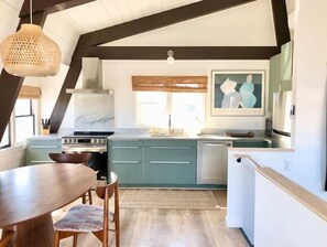 Una cocina con armarios color turquesa, una estufa y un comedor con mesa y sillas.