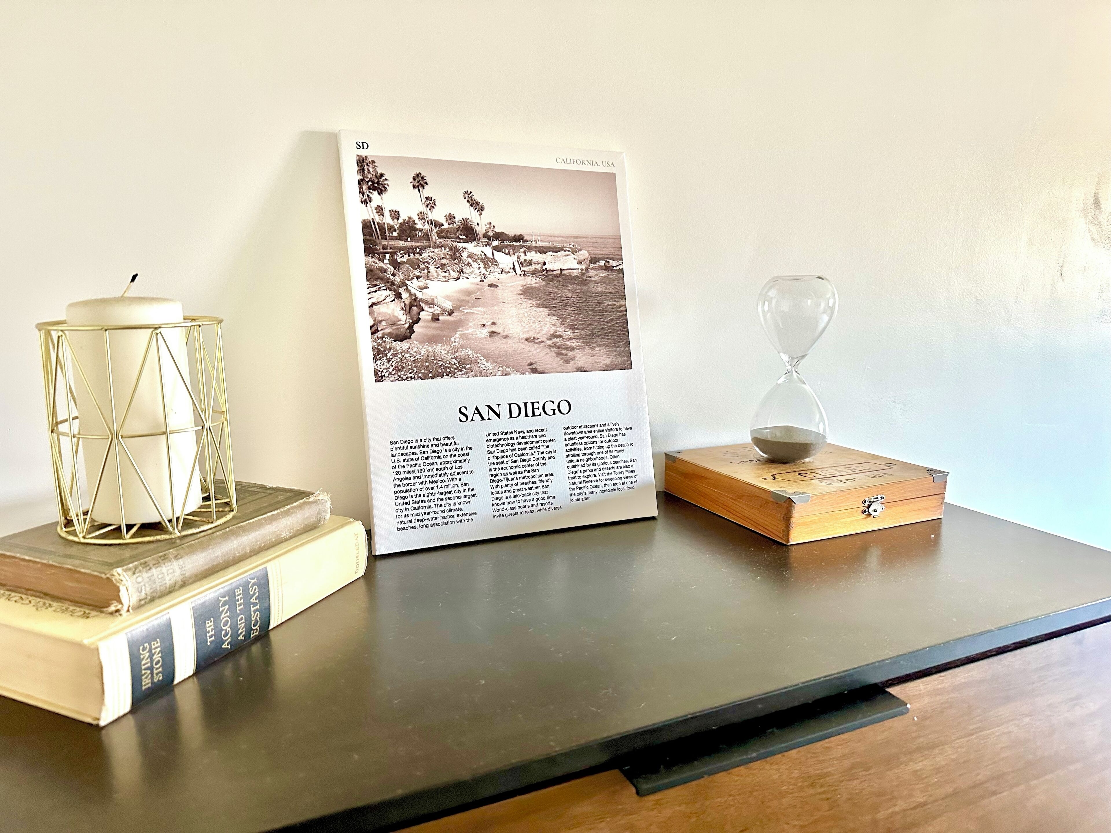A book titled "San Diego" on a table with a candle and an hourglass.