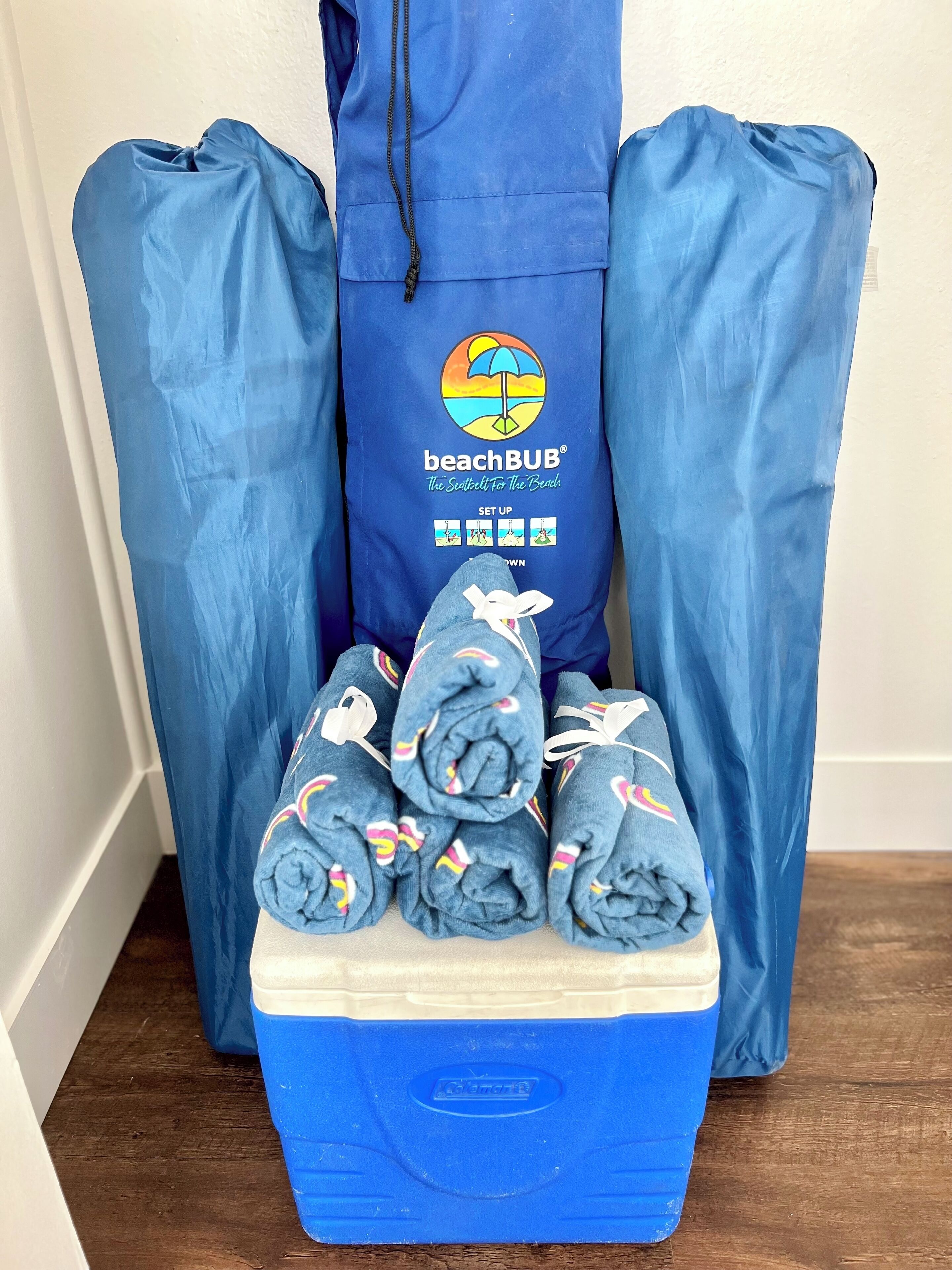 A storage unit with a blue BeachBUB logo, containing rolled towels and a cooler.
