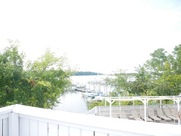 A marina with boats docked, surrounded by greenery and a white pergola with seating.