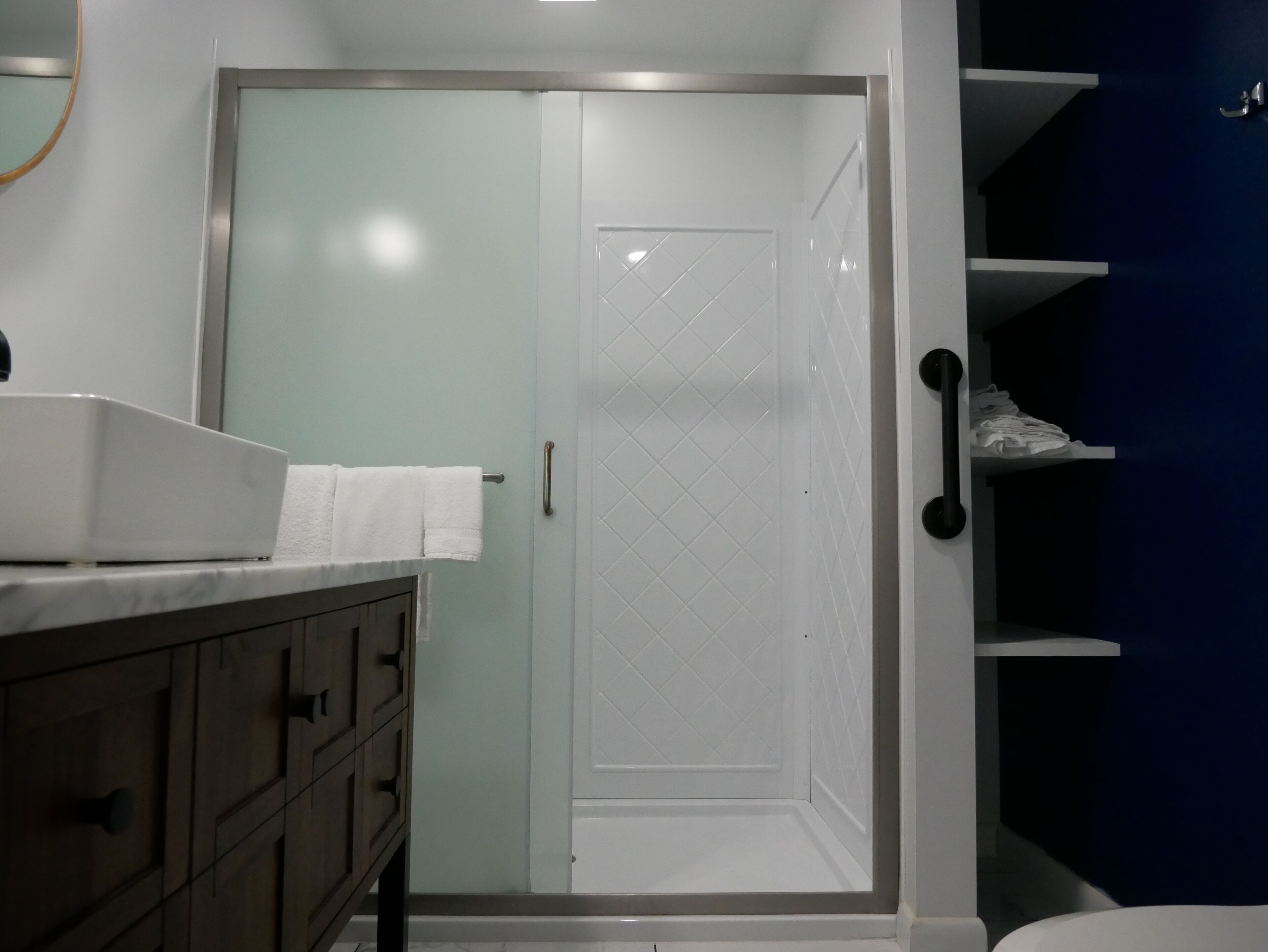 A modern bathroom with a shower, a vanity with a mirror, and a towel rack.
