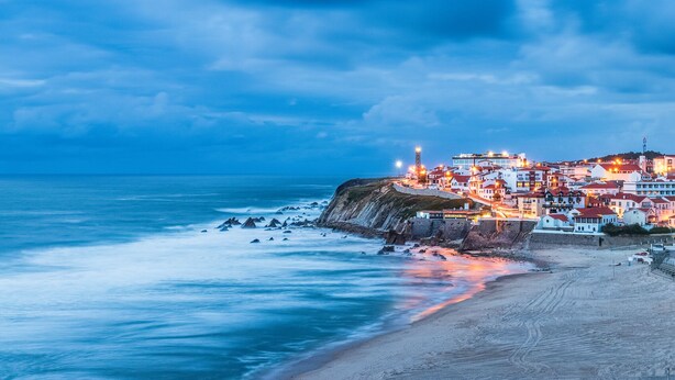 A coastal town with buildings along the cliffside, a lighthouse, and a beach. - Perfect refuge in the city heart, 2 mins from the river, lakes and green spaces (Leiria)