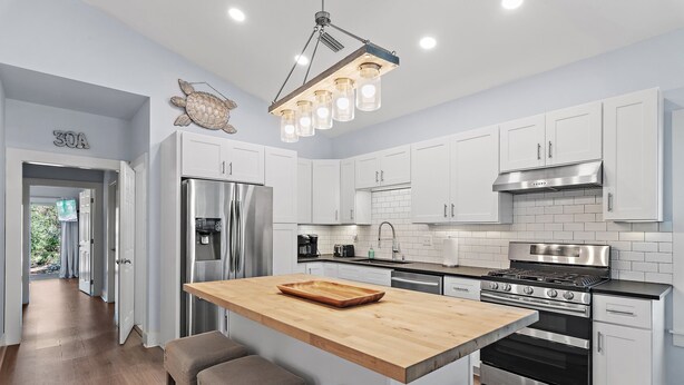 A modern kitchen with white cabinets, stainless steel appliances, and a wooden island with bar stools. - Family Friendly | Walk to Beach & Dining | Firepit (Santa Rosa Beach)