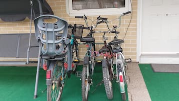 Bicycles parked on the artificial turf, adjacent to a building with a brick facade.