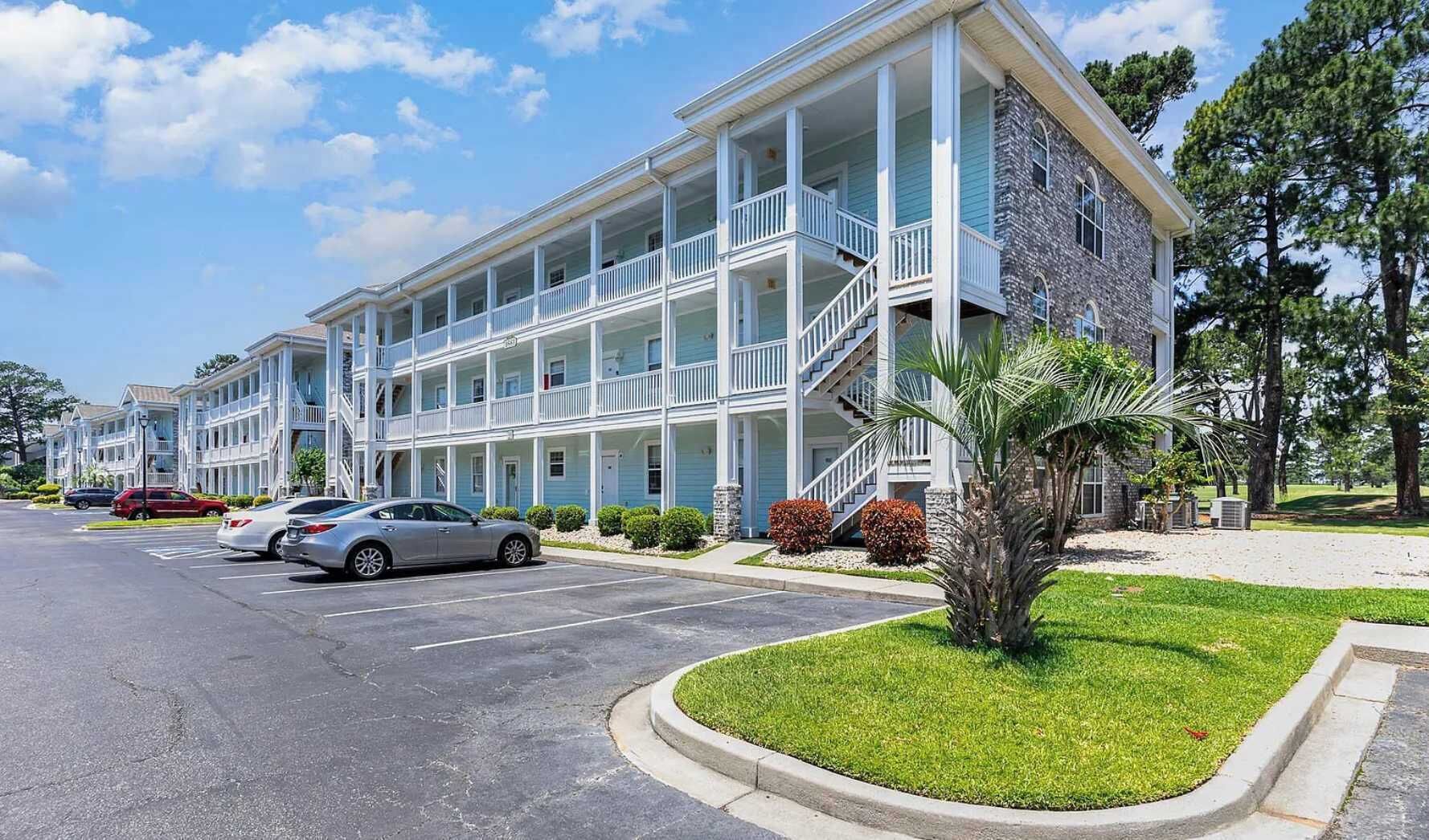 A multi-story motel with a central courtyard, featuring balconies and a stone facade.