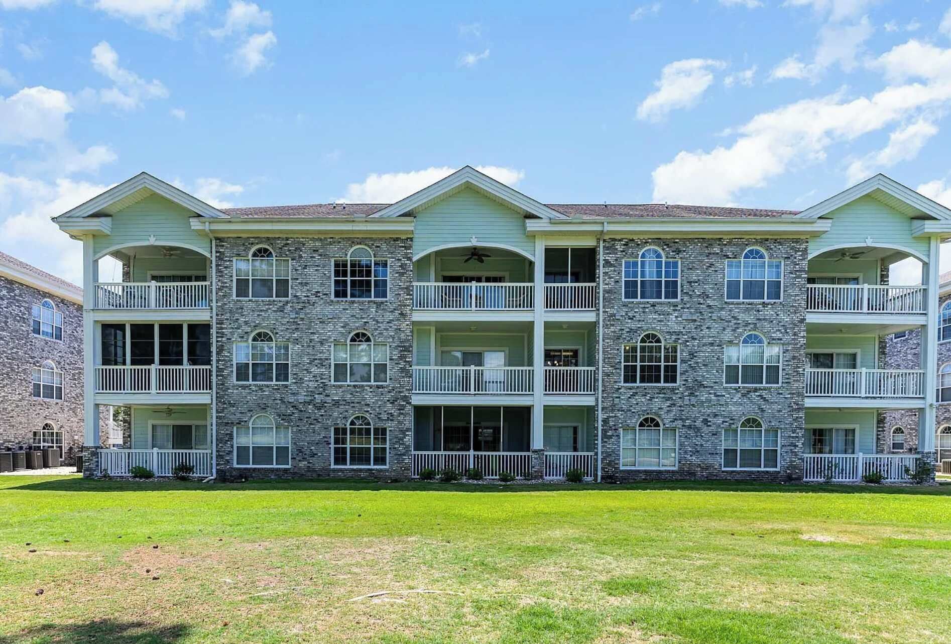 A multi-story building with a stone facade, multiple balconies, and a flat roof.