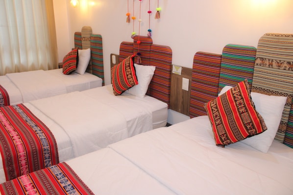 Una habitación de hotel con tres camas, cada una con un cabecero a rayas y una manta decorada.