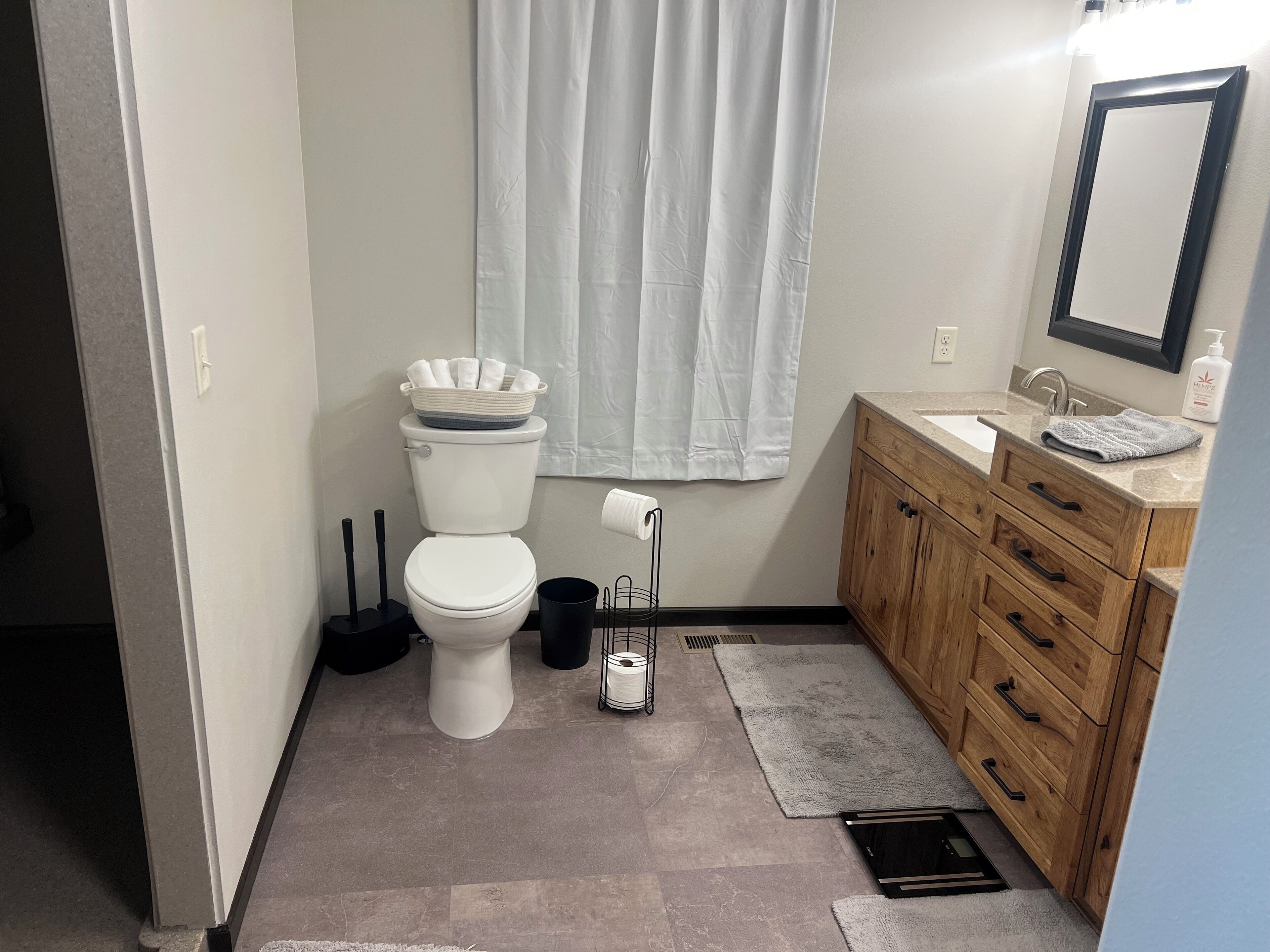 A bathroom with a toilet, sink, and wooden cabinet.