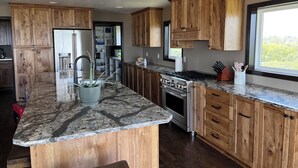 Una cocina moderna con armarios de madera, encimera de granito, estufa integrada y ventana con vistas.