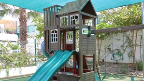A wooden play structure with a slide and climbing elements. - Azul Marino El FARO (Mazatlán)