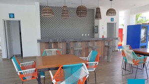 A modern dining area with a wooden table and colorful chairs, a patterned wall, and hanging lights. - Azul Marino El FARO (Mazatlán)