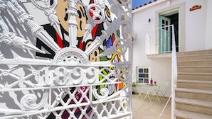 Un edificio blanco con barandillas ornamentales blancas y un mural colorido.