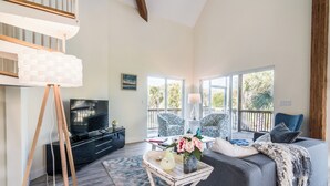 A spacious living room with a large window, a sofa, a TV, and a decorative table.