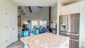 A spacious kitchen with a large island, stainless steel appliances, and a staircase leading to a loft area.