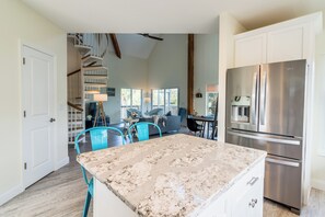 A spacious kitchen with a large island, stainless steel appliances, and a staircase leading to a loft area.