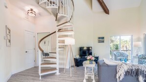 A spacious living area with a spiral staircase, a grey sofa, and a television.