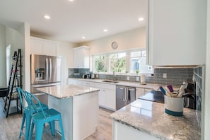 A modern kitchen with stainless steel appliances, white cabinetry, and a large island with seating.