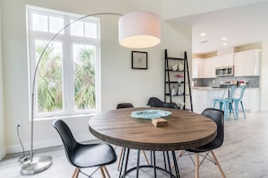 A modern dining area with a round wooden table, black chairs, and a pendant light.