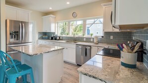 A modern kitchen with white cabinets, stainless steel appliances, and a granite countertop.