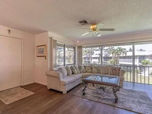 Relax in this inviting living room with a sofa, coffee table, and ceiling fan, offering a view of the outdoors.