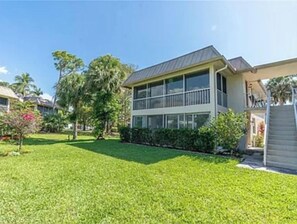 Stunning two-story residence with a flat roof and balcony, set amidst lush lawns and tropical trees.