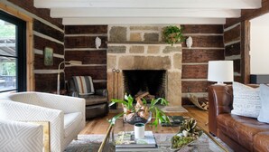 A cozy living room with a stone fireplace, leather sofas, a glass coffee table, and a view of the outdoors. - The Peregrine: Flat Mountain Farm - expansive luxury home on historic 28 acre rhododendron farm (Highlands)