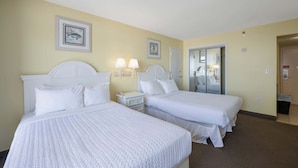 Une chambre d’hôtel avec deux lits, une table de chevet, des lampes fixées au mur et une porte donnant accès à une salle de bain.