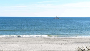 Une plage avec un bateau visible au loin et un ciel dégagé.