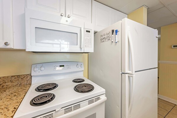 A kitchen with white appliances, including a microwave, oven, and refrigerator.
