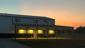 A two-story building with a covered porch and a driveway. - The Great Plains Escape (Enid)