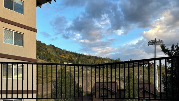 A hot tub with a view of a house and a forested hill in the background. - Mountainside ski-in condo near Ski Time Square  (Steamboat Springs)