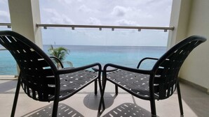 A balcony with two chairs facing a view of the ocean.