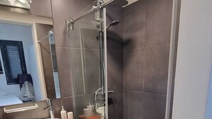 A modern bathroom with a glass-enclosed shower, a wooden vanity, and a large mirror.