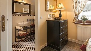 Un baño con piso a cuadros blanco y negro, un lavamanos, un espejo y un mueble con cajones.