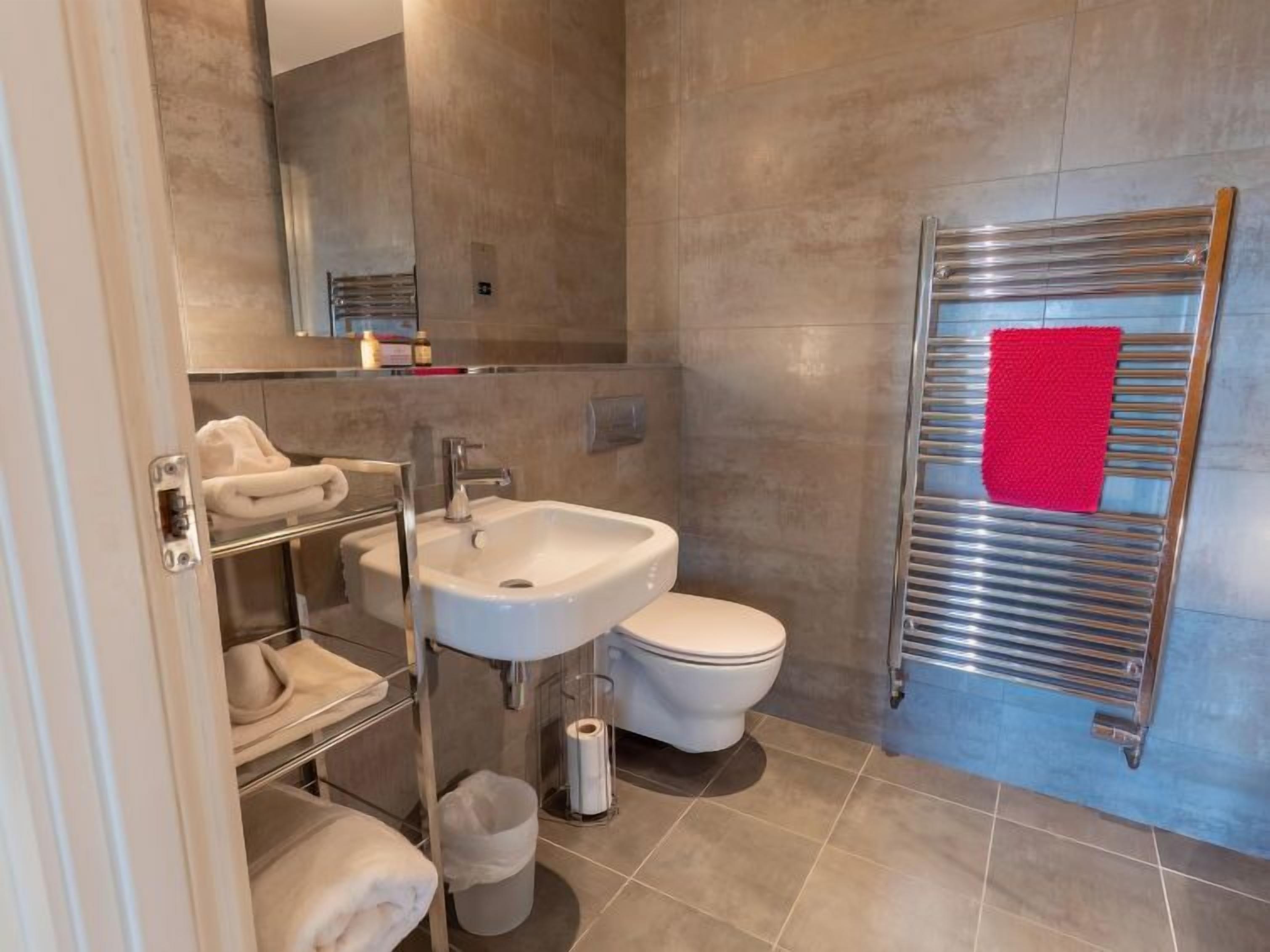 A modern bathroom with a sink, toilet, and towel rack.