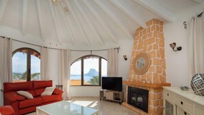 Ein geräumiges Wohnzimmer mit einem roten Sofa, einem Glastisch, einem Kamin und einem Fernseher.