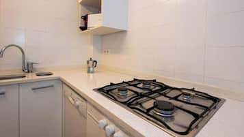 Een koelkast, een oven, een vaatwasser, kookgerei, borden en bestek