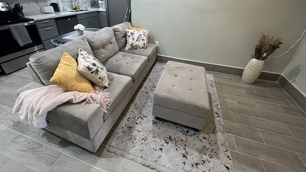 A modern living room with a grey sofa, ottoman, and a world map artwork on the wall. - EADO 3BR Downtown Houston home (Houston)