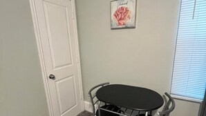 A small room with a white door, a round table with four chairs, a framed artwork on the wall, and a window with blinds. - EADO 3BR Downtown Houston home (Houston)
