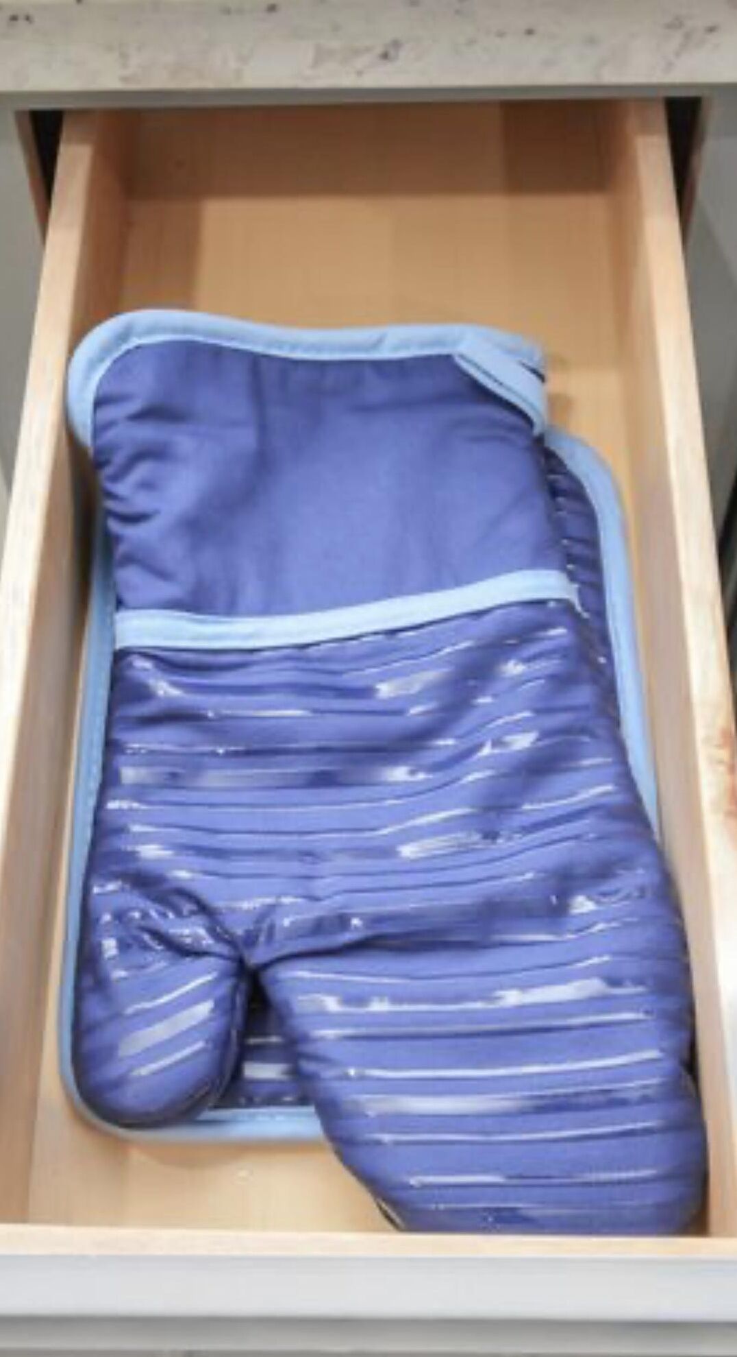A drawer containing a blue garment with a zipper.