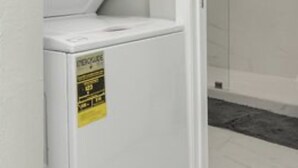 A laundry room with stacked washers and dryers, a tiled shower area, and a white wall. - EADO 3BR Downtown Houston home (Houston)