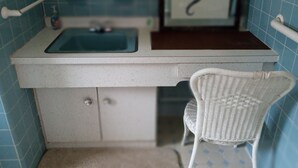 A bathroom with a white sink, a mirror, and a white wicker chair.