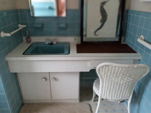 A bathroom with a white sink, a mirror, and a white wicker chair. - Exclusive PRIVATE Beach for 1 Home ONLY + Oceanfront Pool (Mantoloking)