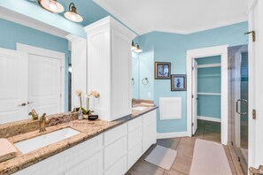 A modern bathroom with two sinks, a vanity, and a shower area.