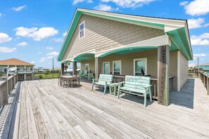 A wooden deck with outdoor seating and a covered area, overlooking a body of water.